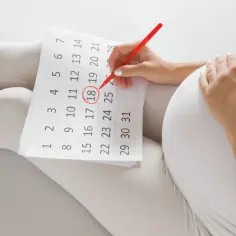 Ciężarna kobieta zaznacza na kalendarzu 18. dzień, licząc który tydzień ciąży.