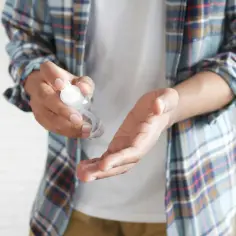 Dłoń aplikuje płyn dezynfekujący z oktenidyną na drugą dłoń, dbając o higienę.